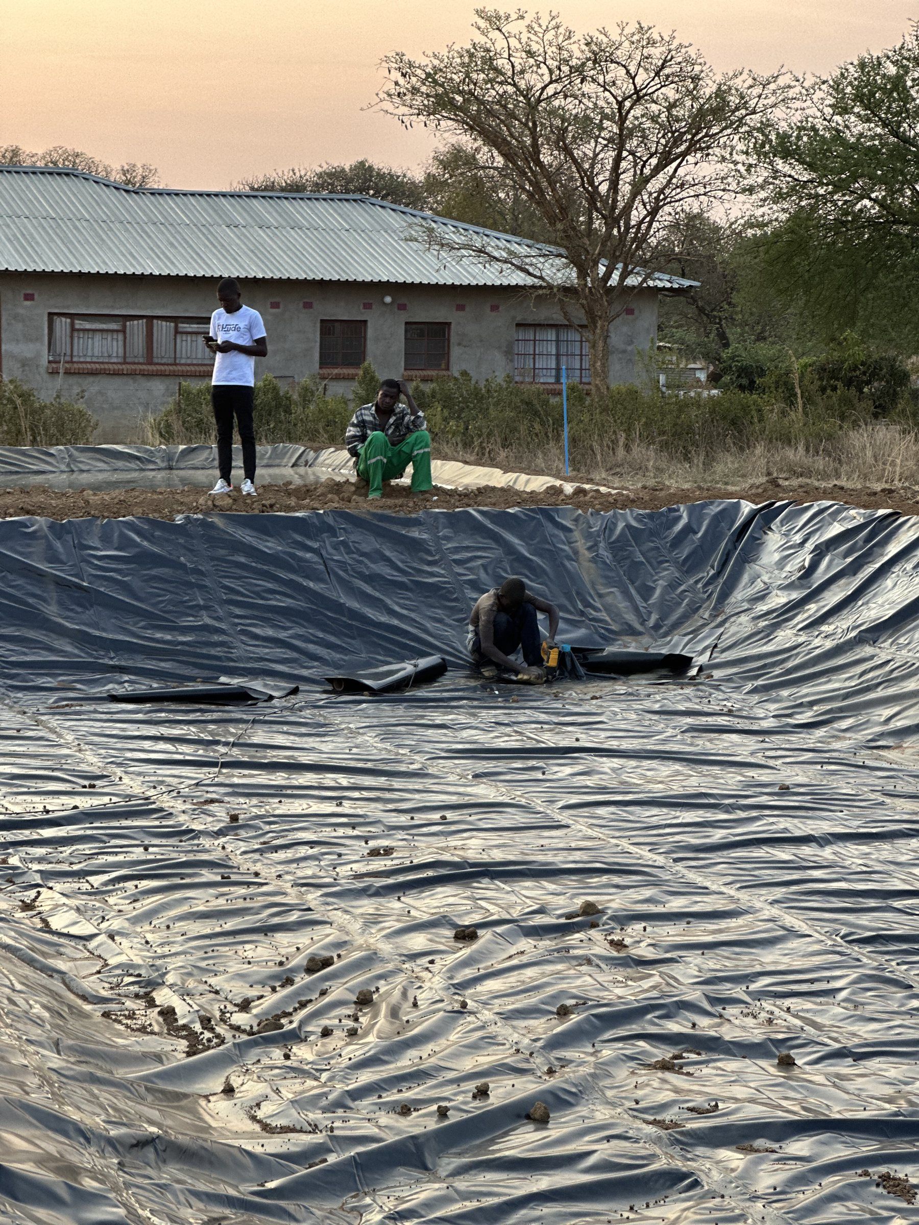 The crew fitting liner inside a newly dug pond