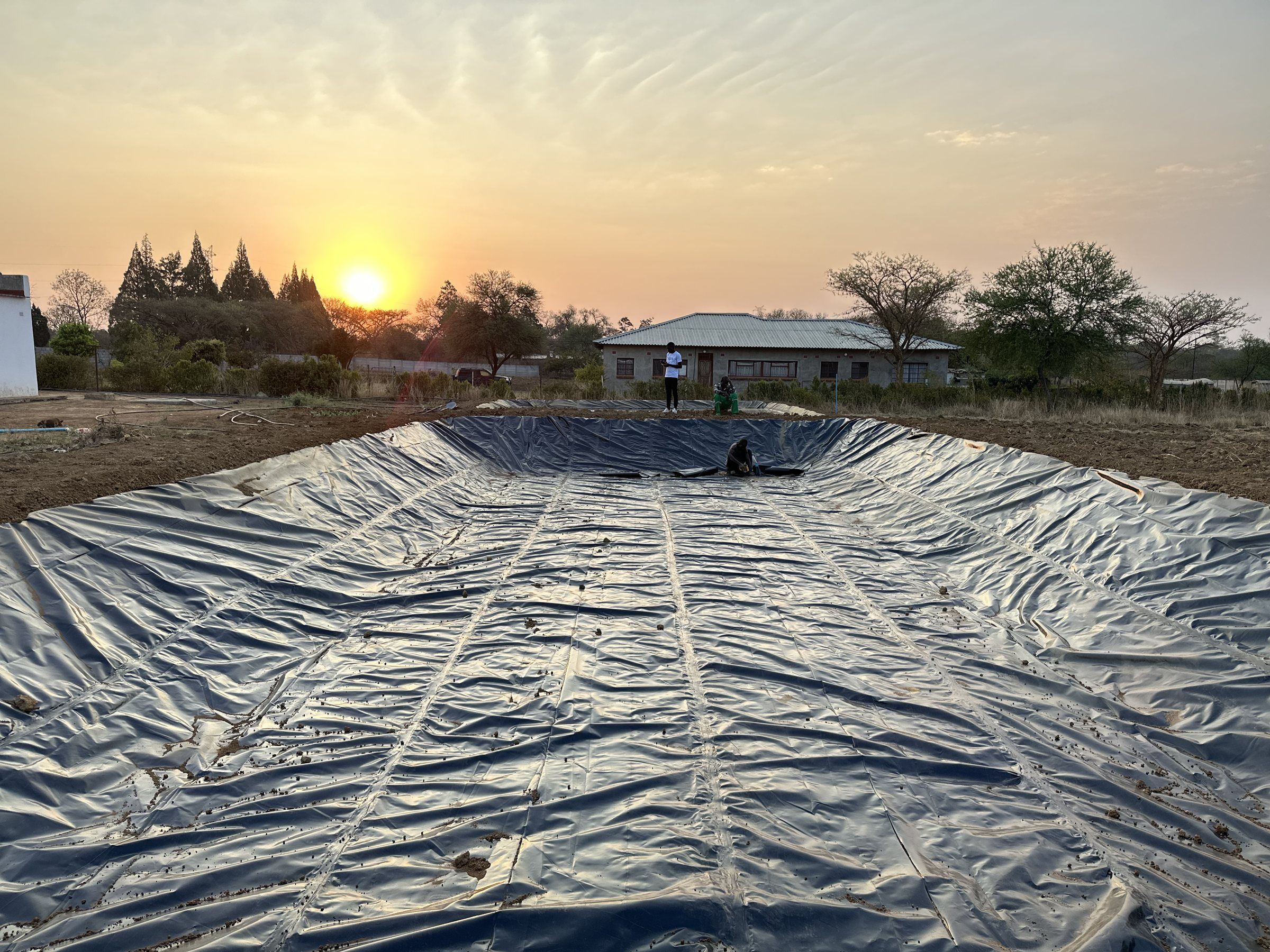 A large pond freshly lined with black liner at sunset