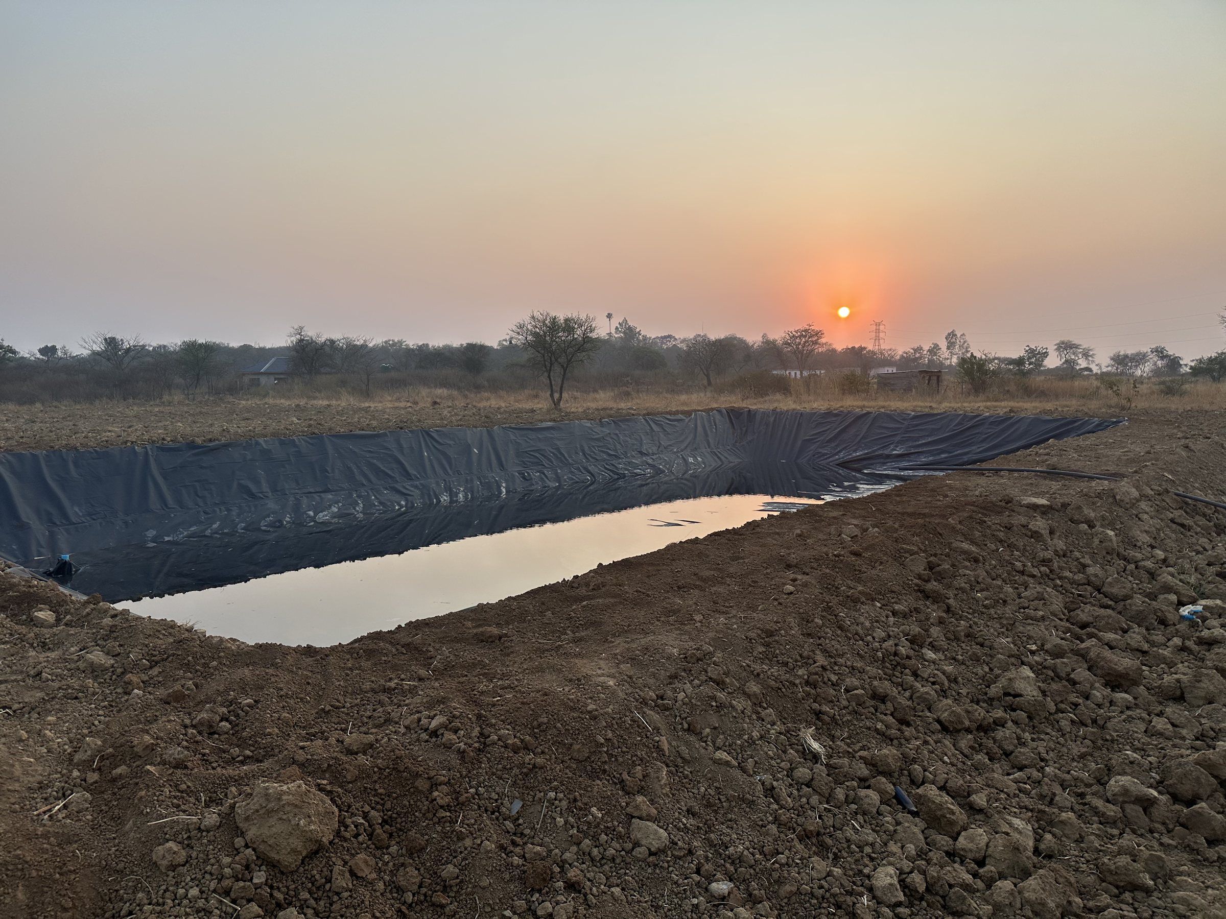 A newly lined pond with a little water in it at sunrise